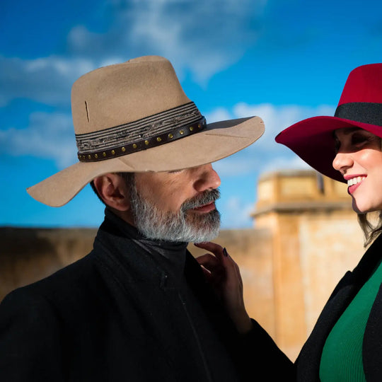 cappello con tesa a taglio vivo rosso rubino e cappello country beige in feltro di lana merinos antipioggia primario nesti coppia in esterno e cielo azzurro