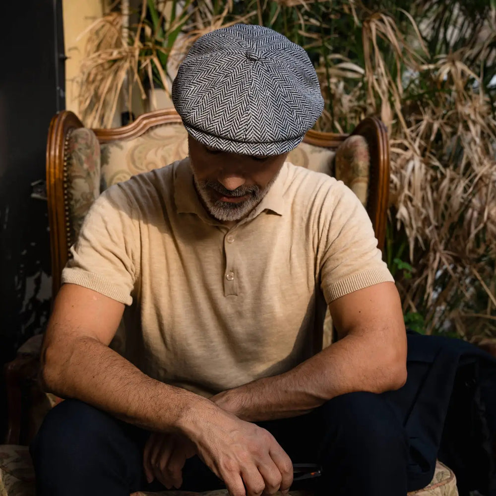 modello adulto con abbigliamento casual chic e coppola peaky blinder spigata in lana primario nesti su poltrona vintage