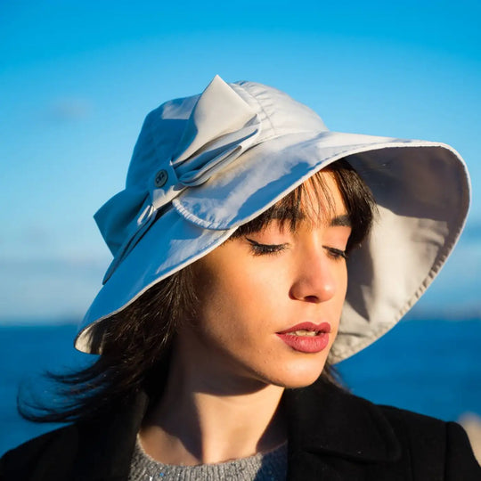 bucket impermeabile primario nesti grigio perla con fiocco modella dai tratti orientali cielo intenso che si fonde con il colore del cappello