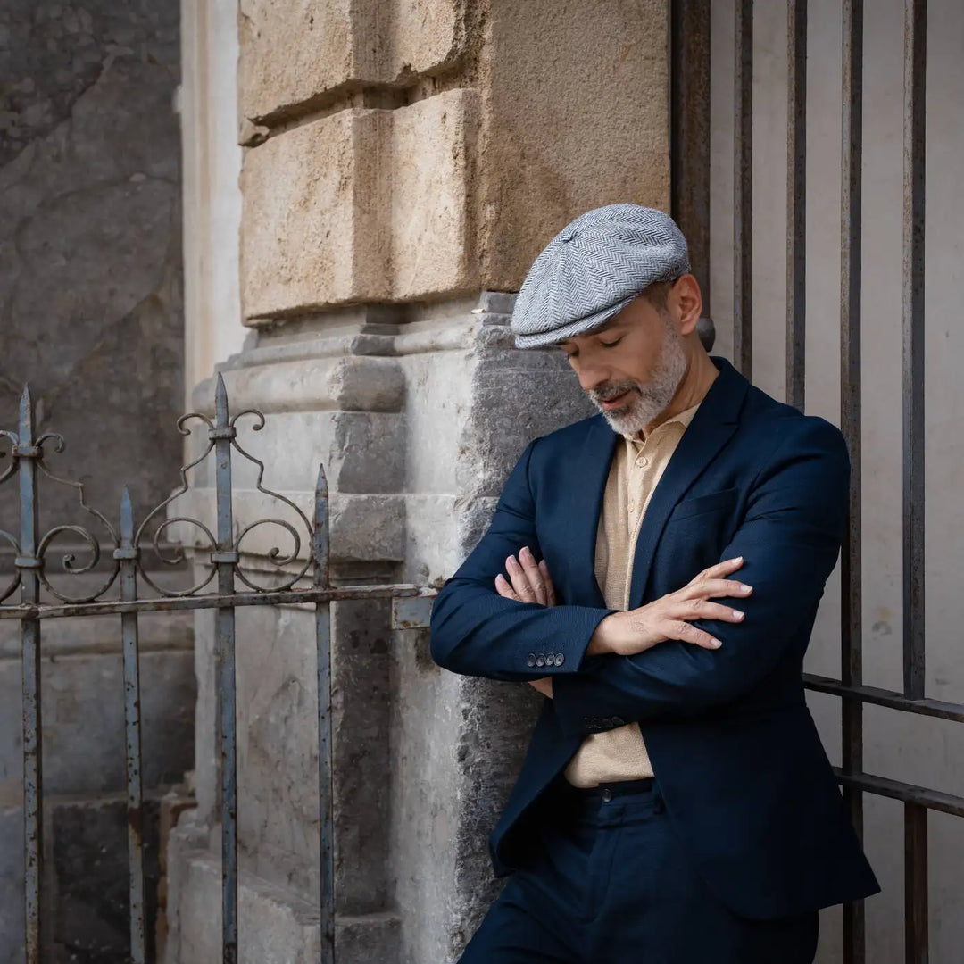 modello adulto con barba indossa una coppola peaky blinder spigata primario nesti e sfoggia il suo outfit navy contemporaneo