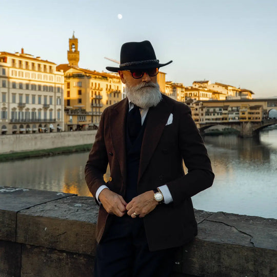 modello distinto con cappello australiano primario nesti in lana merinos indossa un completo scuro con sfondo di tramonto suggestivo sullarno