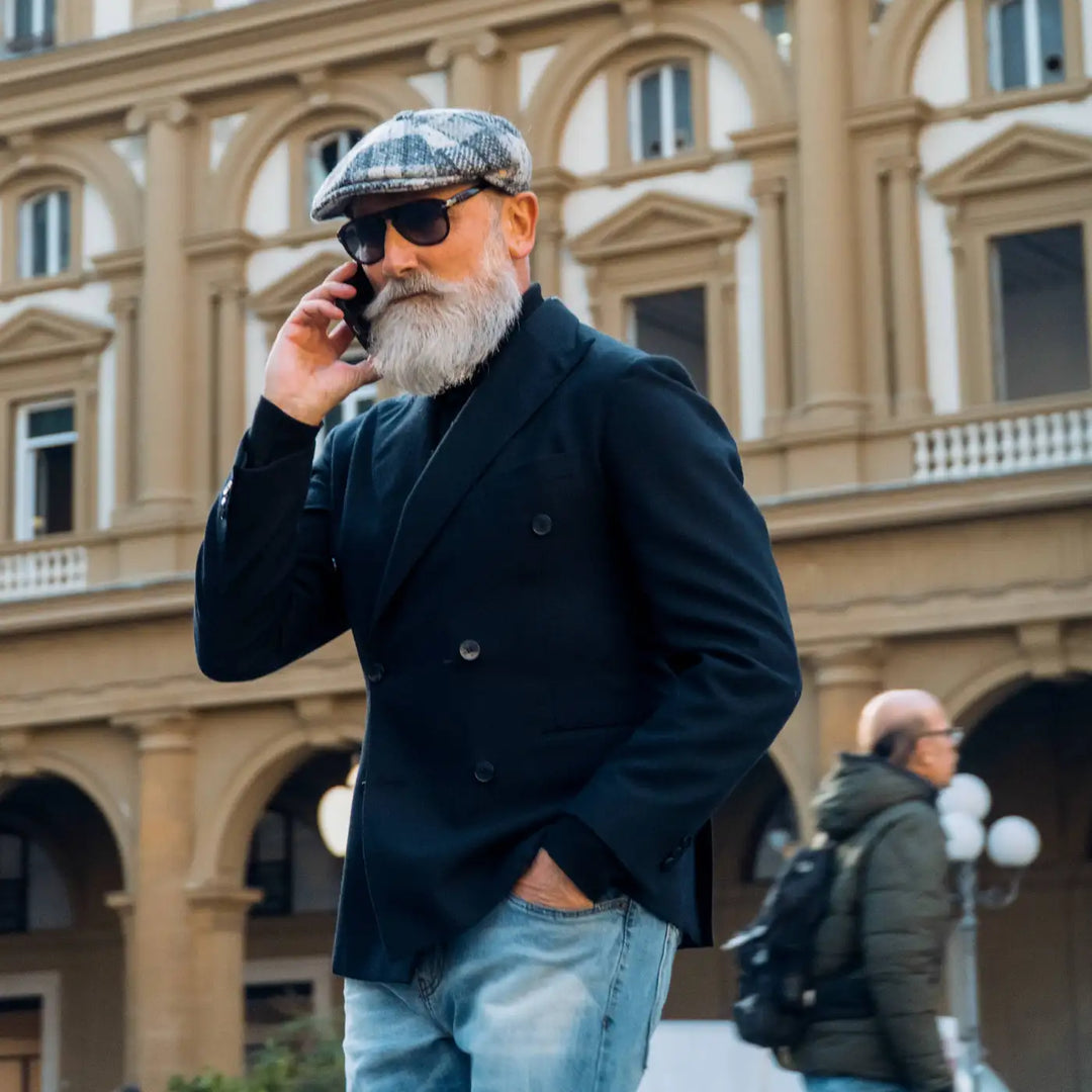 modello elegante con coppola peaky blinders di lana in fantasia chiara primario nesti indossa un outfit casual business tra le arcate storiche di firenze