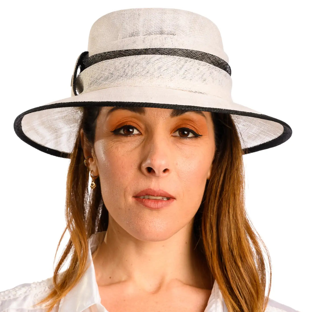 primo piano frontale di donna adulta con capelli lunghi che indossa un cappello da cerimonia estivo elegante color bianco nero realizzato da primario nesti