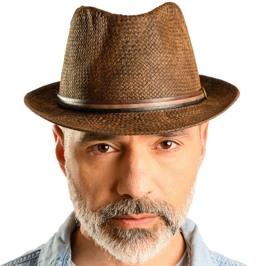 primo piano frontale di uomo con barba che indossa un cappello trilby a tesa corta stonewashed color marrone fatto da cappelleria primario nesti