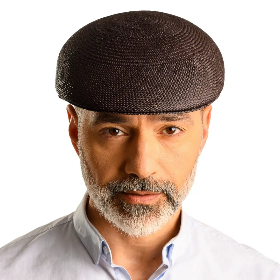 primo piano frontale di uomo con barba che indossa un coppola siciliana estiva di panama color nero fatto da cappelleria primario nesti