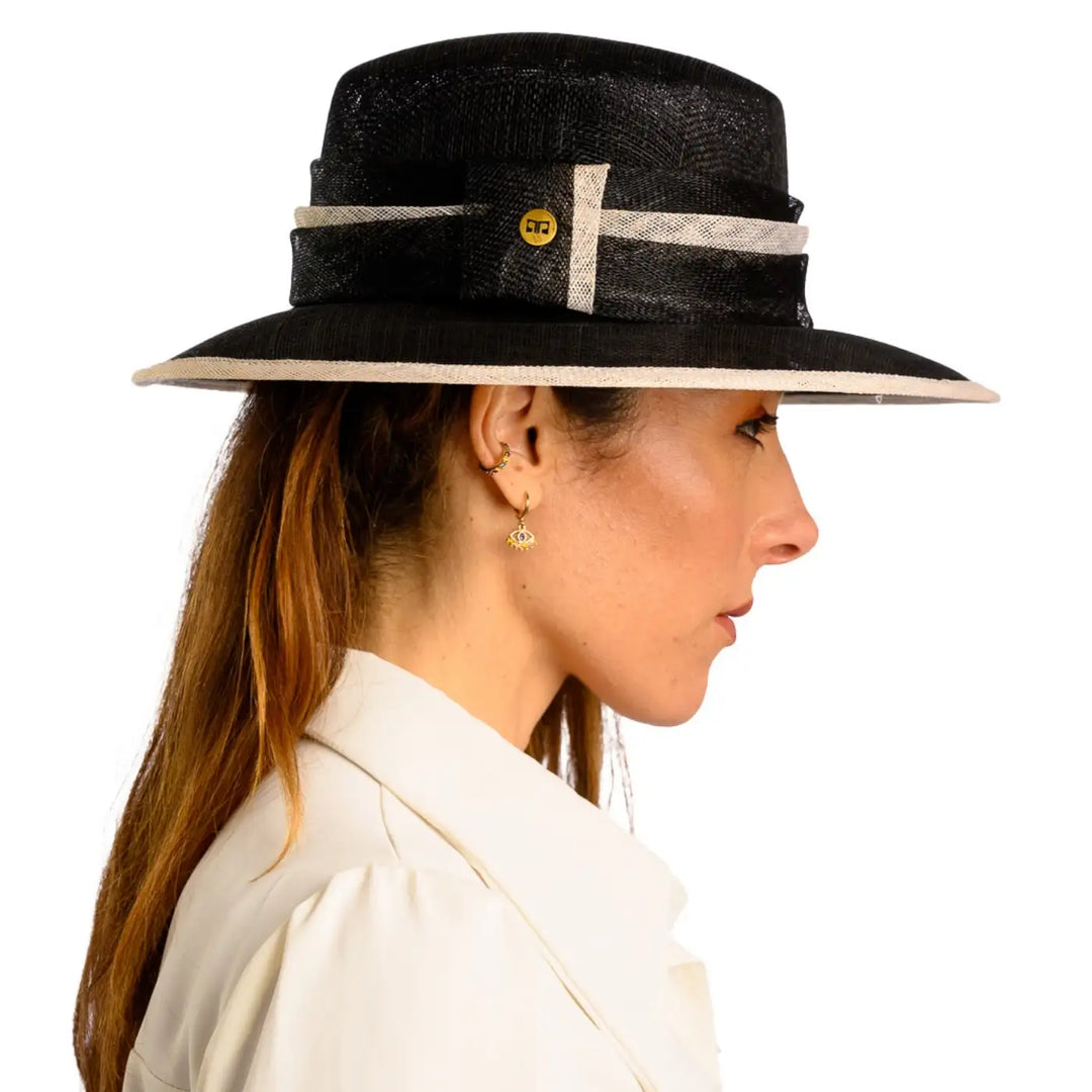 primo piano laterale di donna adulta con capelli lunghi che indossa un cappello da cerimonia estivo elegante color nero bianco realizzato da primario nesti