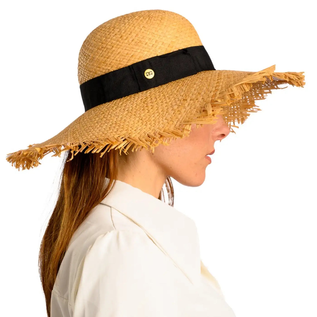 primo piano laterale di donna adulta con capelli lunghi che indossa un cappello da sole a tesa larga in rafia color paglia realizzato da primario nesti
