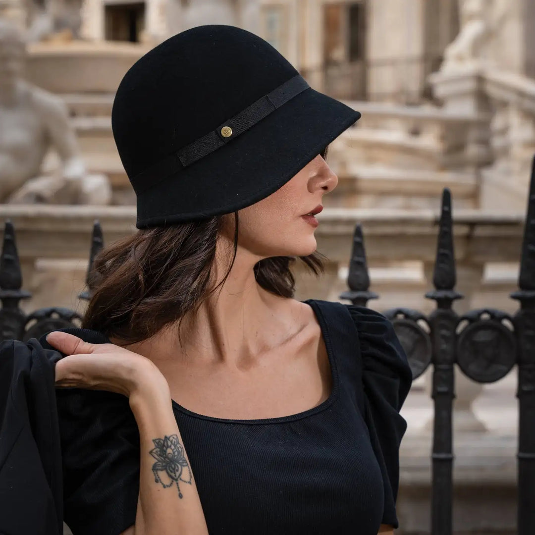 ritratto di modella adulta con cappello a cloche signorile a tesa media primario nesti nero recinzione storica di sfondo