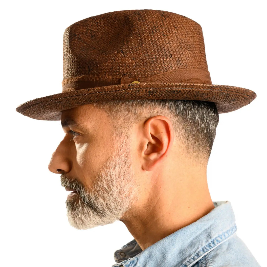 vista laterale di un uomo con barba che indossa un cappello trilby a tesa media stonewashed color marrone fatto a mano da cappelleria primario nesti