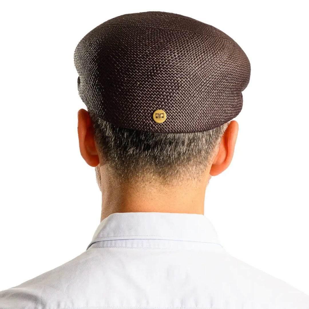 vista posteriore di un uomo con barba che indossa un coppola siciliana estiva di panama color nero fatto a mano da cappelleria primario nesti