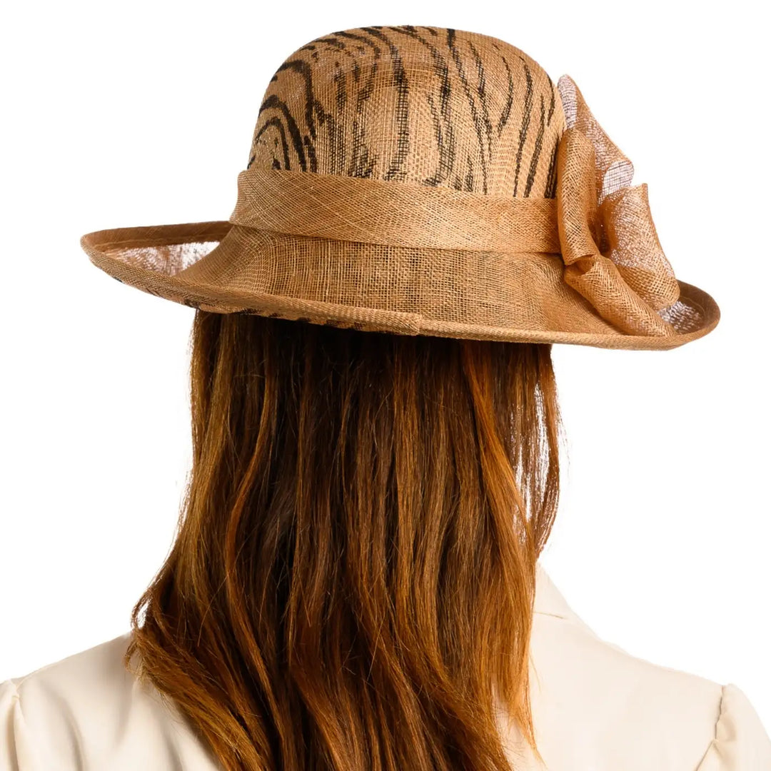 vista posteriore di una donna con capelli lunghi che indossa un cappello da cerimonia estivo con fiocco color camel animalier fatto a mano da primario nesti