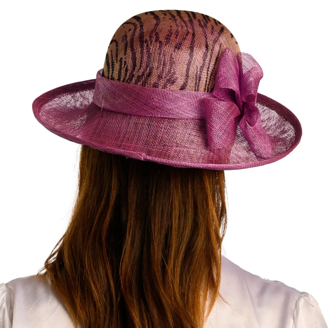vista posteriore di una donna con capelli lunghi che indossa un cappello da cerimonia estivo con fiocco color ciclamino animalier fatto a mano da primario nesti