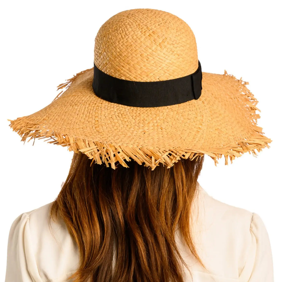 vista posteriore di una donna con capelli lunghi che indossa un cappello da sole a tesa larga in rafia color paglia fatto a mano da cappelleria primario nesti